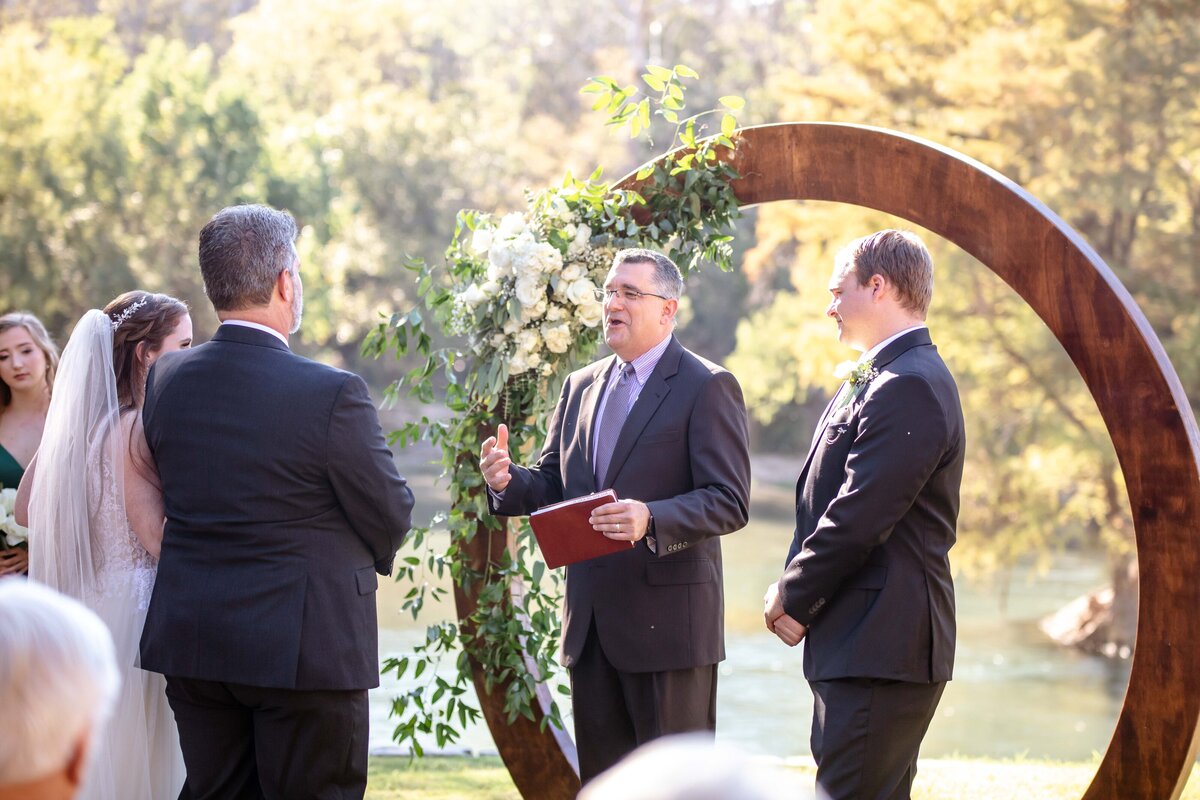 pastor speaks to guests at Milltown Historic District wedding in front of circle alter with flowers