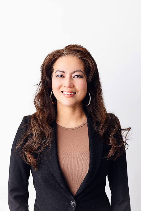 Woman with long brown hair smiles in white studio.