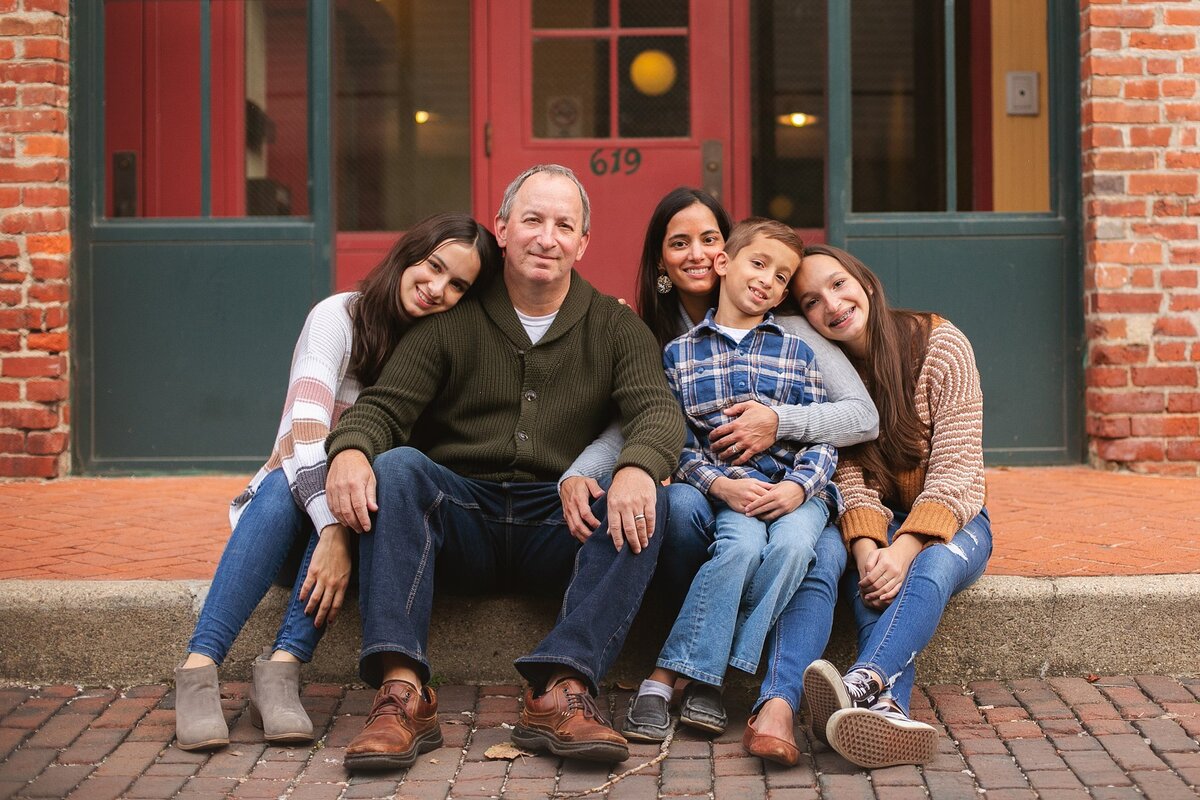 A-family-sitting-together-in-front-of-a-brick-building-in-the-historic-Woodruff-Place-neighborhood-near-Mass-Ave-in-downtown-Indianapolis-during-an-urban-photo-session