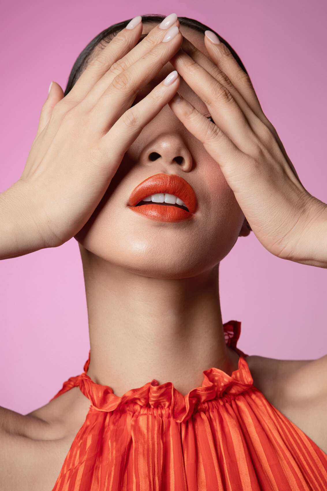 Artistic portrait of Jiaqi covering her eyes with her hands, wearing vibrant red lipstick and jewelry, captured by Ylva Erevall.