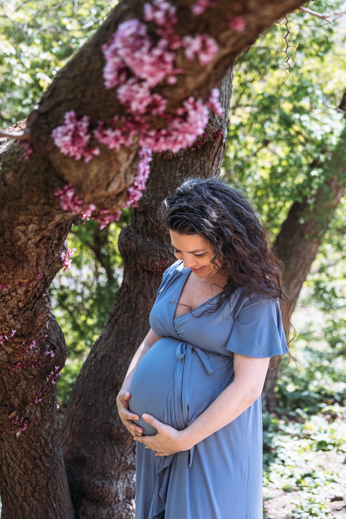 Maternity Photographer, a woman stands in a park, she is expecting and happy