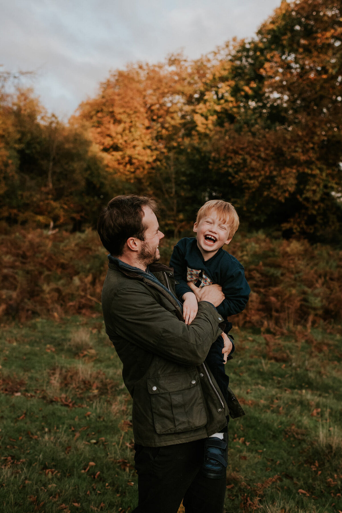 Father holding young son in autumn leaves