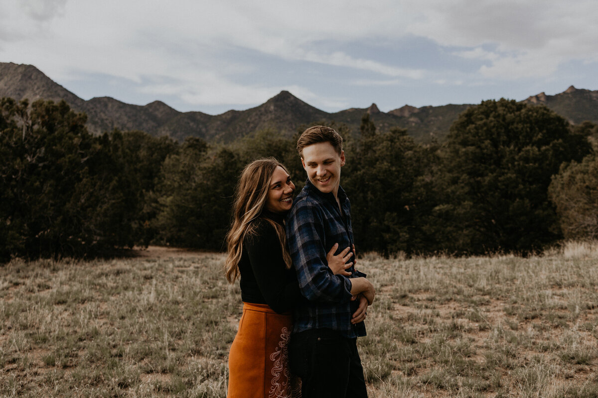 woman holding her fiancé from behind in the desert laughing