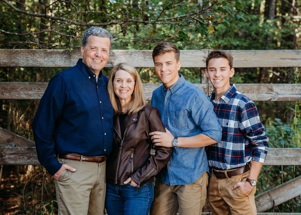 Family portrait with teen boys against a fence.