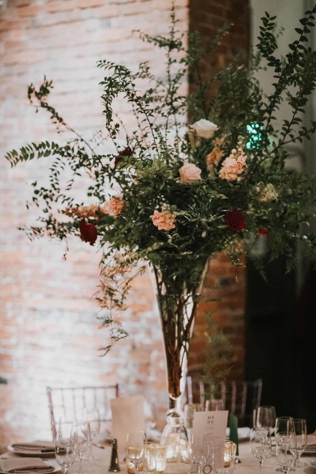 elevated centerpiece of greenery with minimal blush and red flowers at Axis Pioneer Square