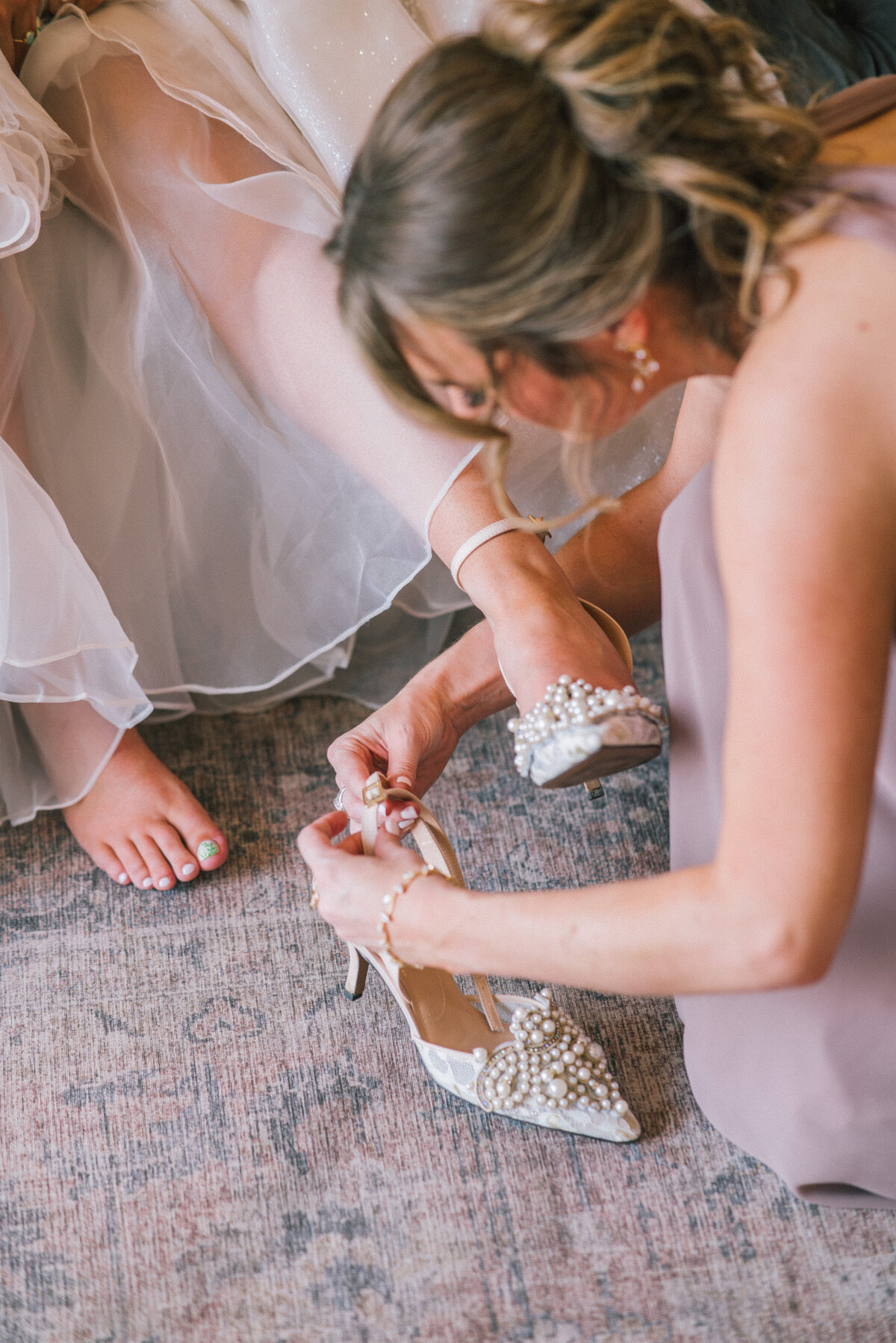 maid of honor helps bride put on pearl wedding shoes at the trillium venue in sevierville tennessee