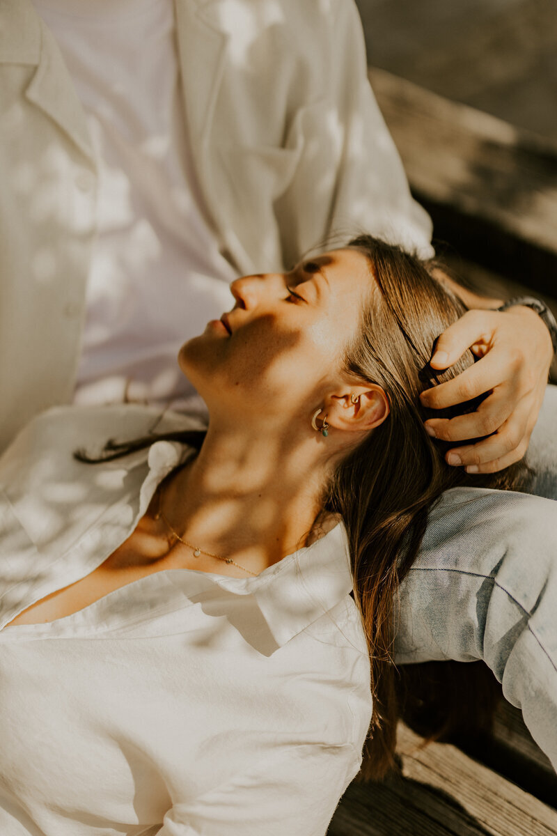 Femme la tête reposant sur les genoux de son homme, qui lui caresse les cheveux pendant une séance avec Laura, photographe professionnelle.