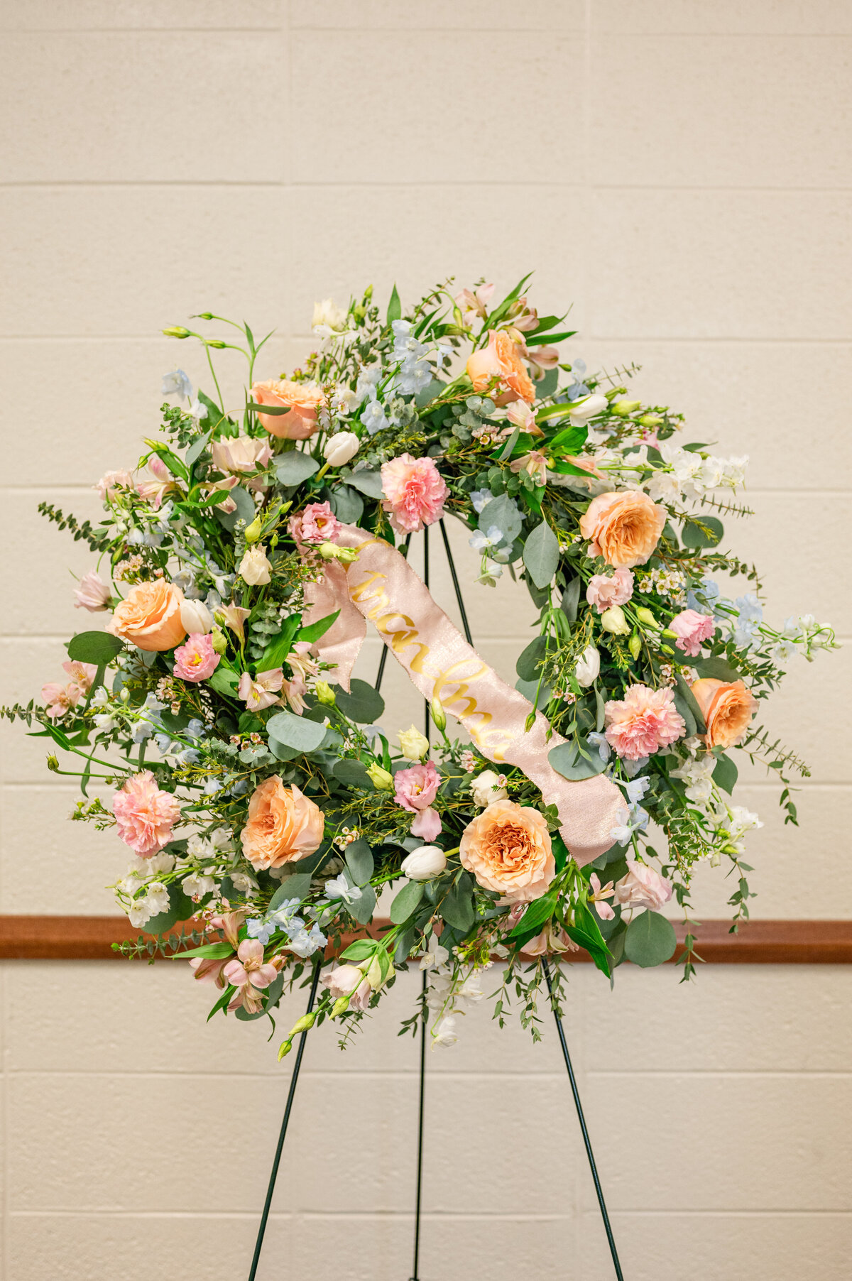 beautiful peach pink white and blue color scheme wreath arrangement for a funeral  