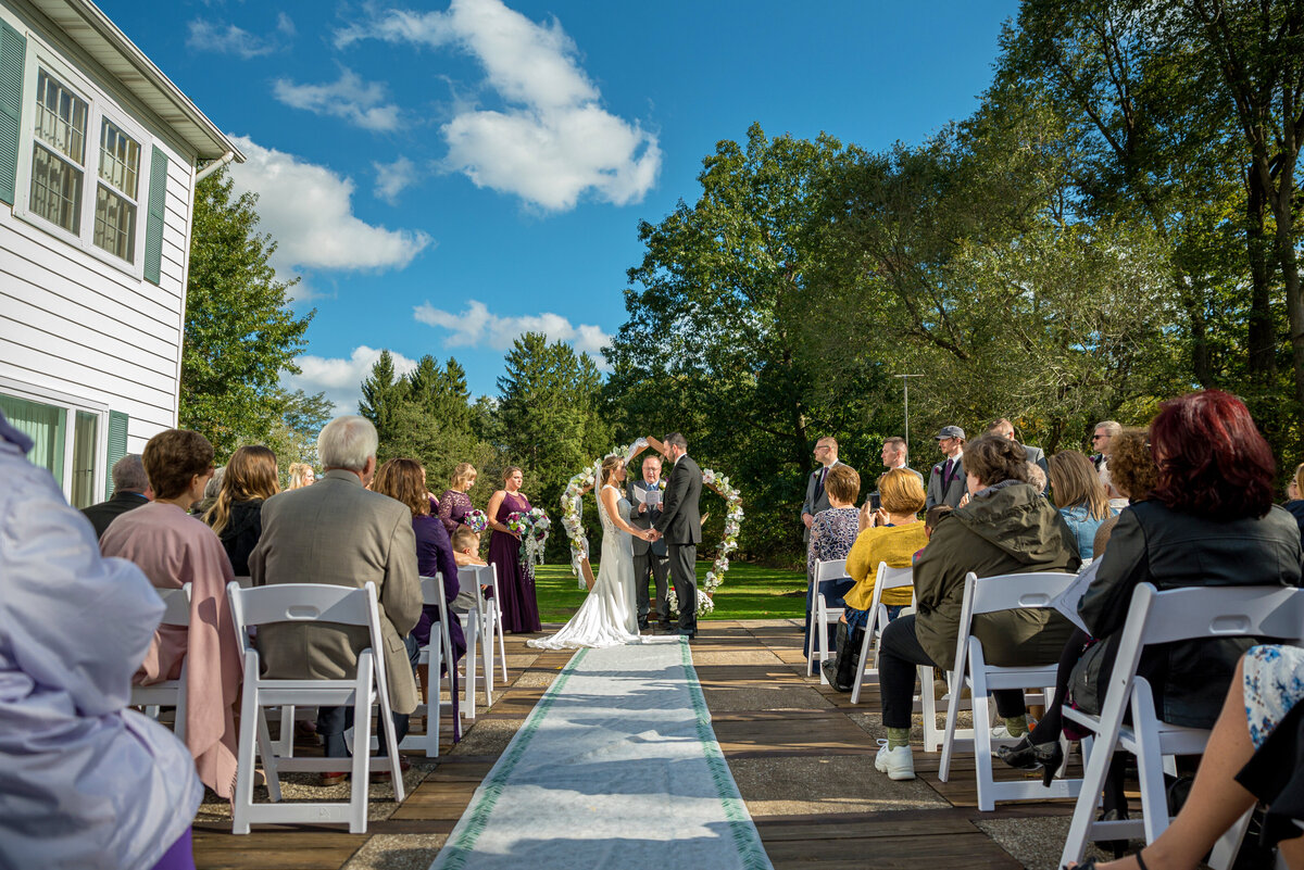 Outdoor wedding ceremony by barn.