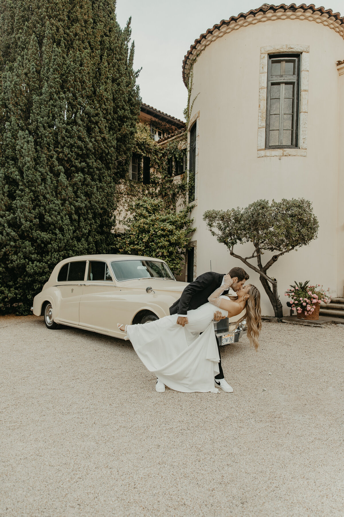 Wedding Photographer & Videographer, groom dipping bride next to getaway car