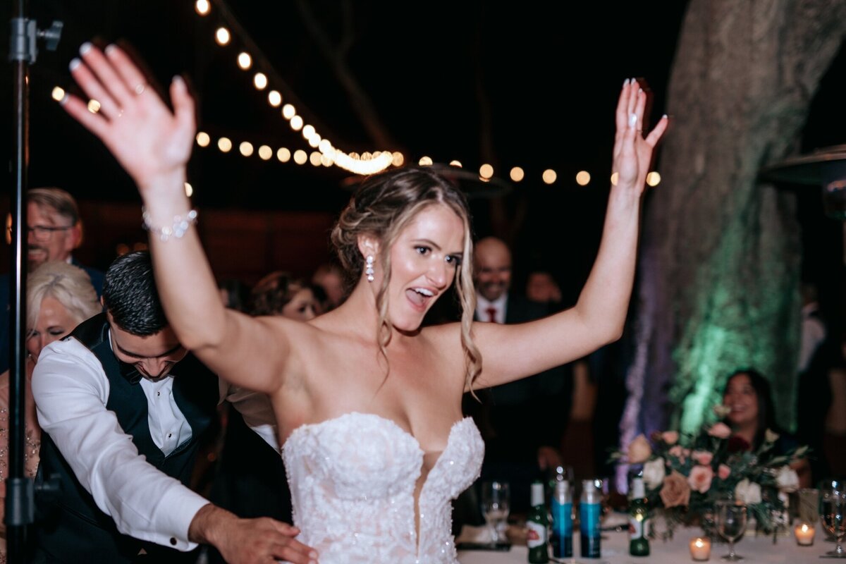 Bride with her hands in the air celebrating and dancing with her new husband.