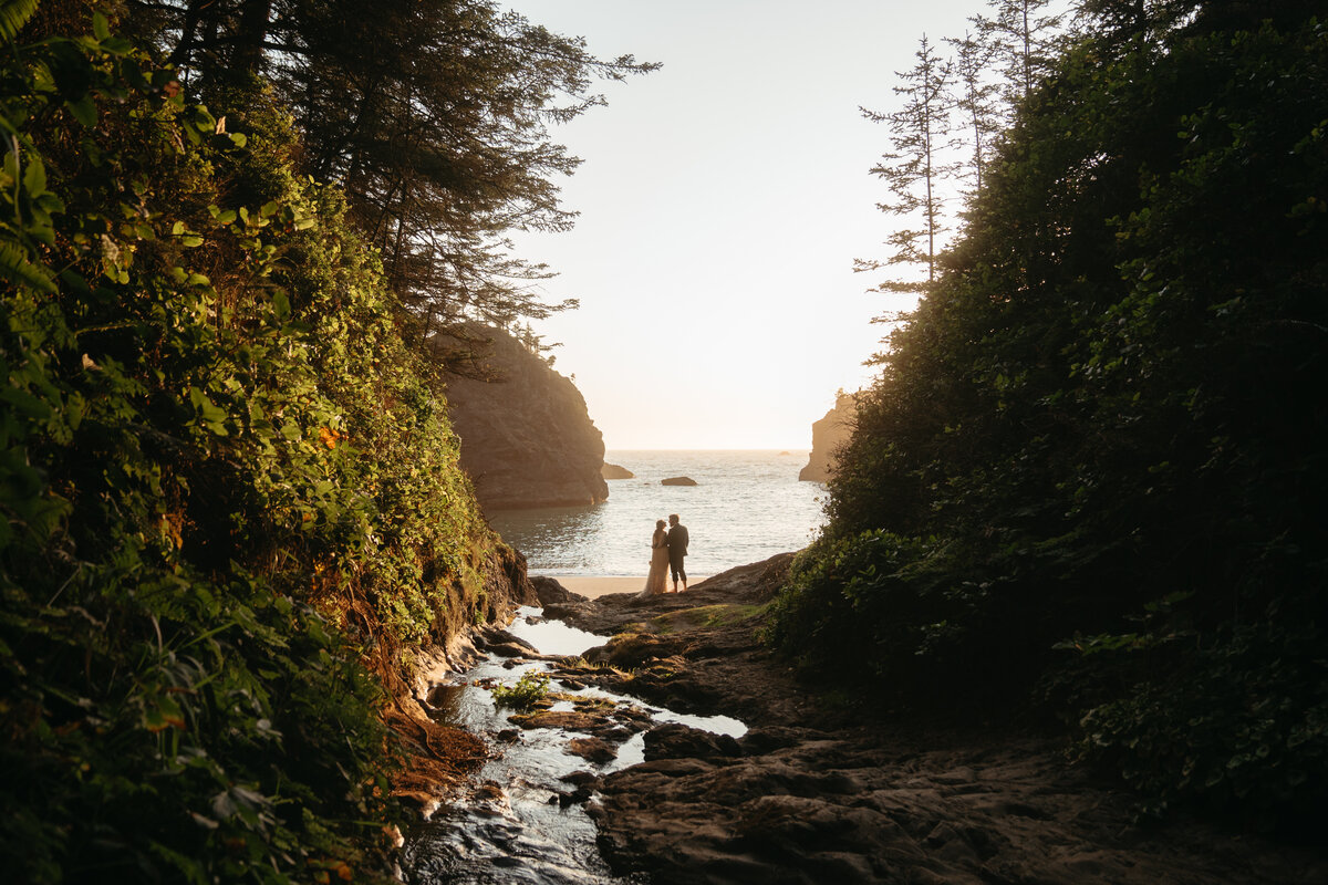 Eloping Ideas | Wedding couple kissing while standing in a unique ocean canyon at sunset