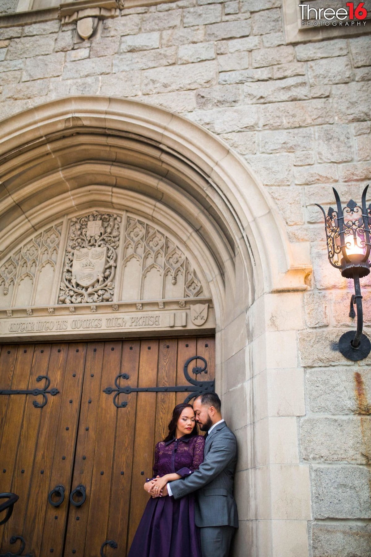 Engaged couple tender pose in front of beautiful door