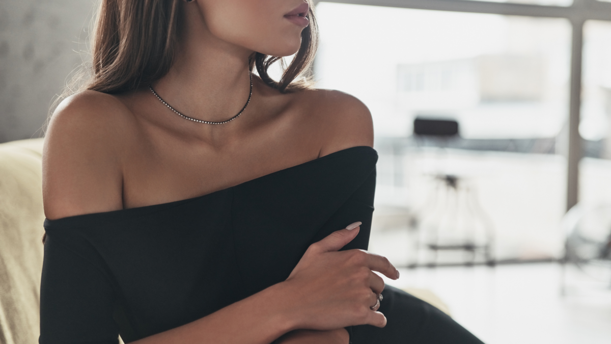 Woman in black off-shoulder top sitting in a modern office space, symbolizing elevated brand design and creative leadership