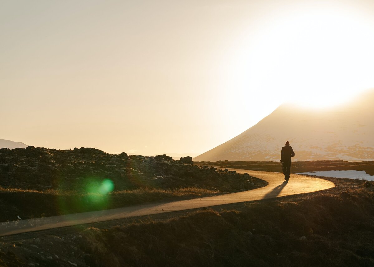 Man walking down a path at sunset
