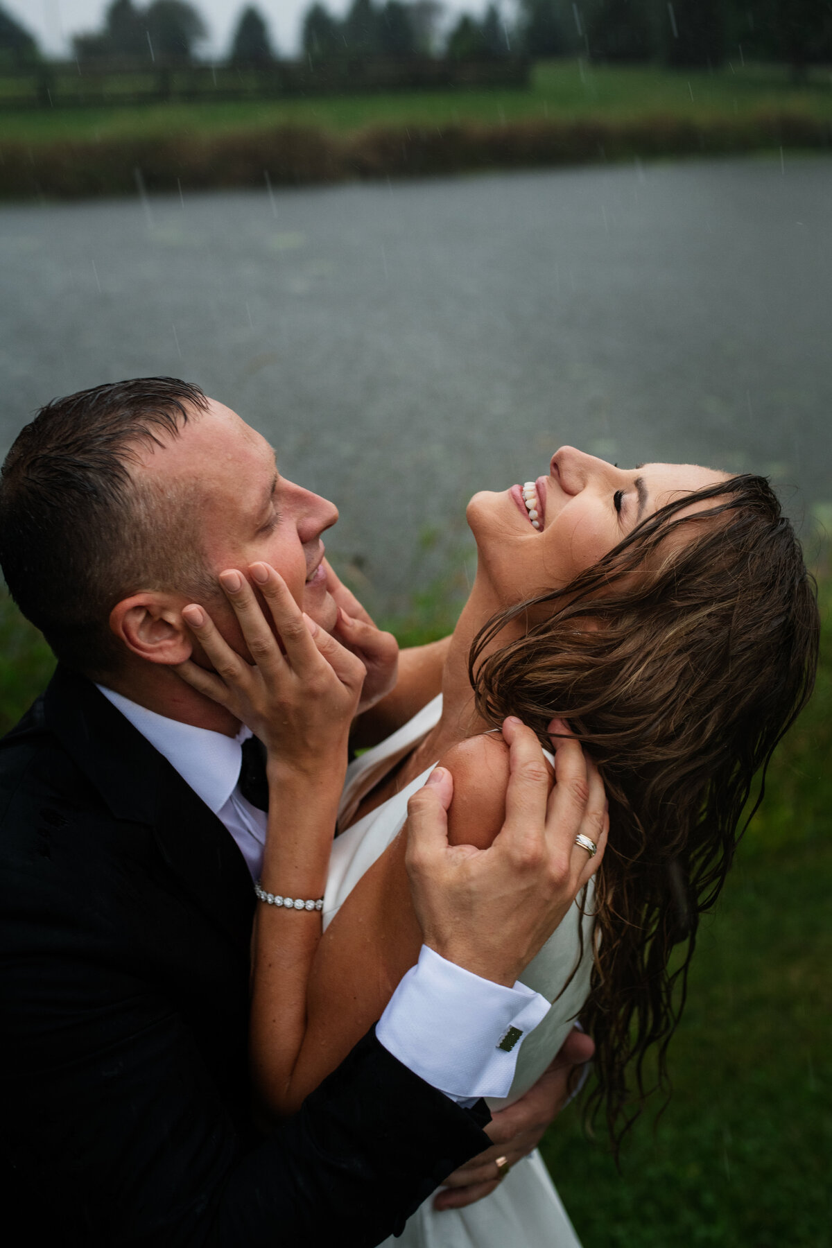 bride and groom looking up to the sky  getting rained on and holding each other close