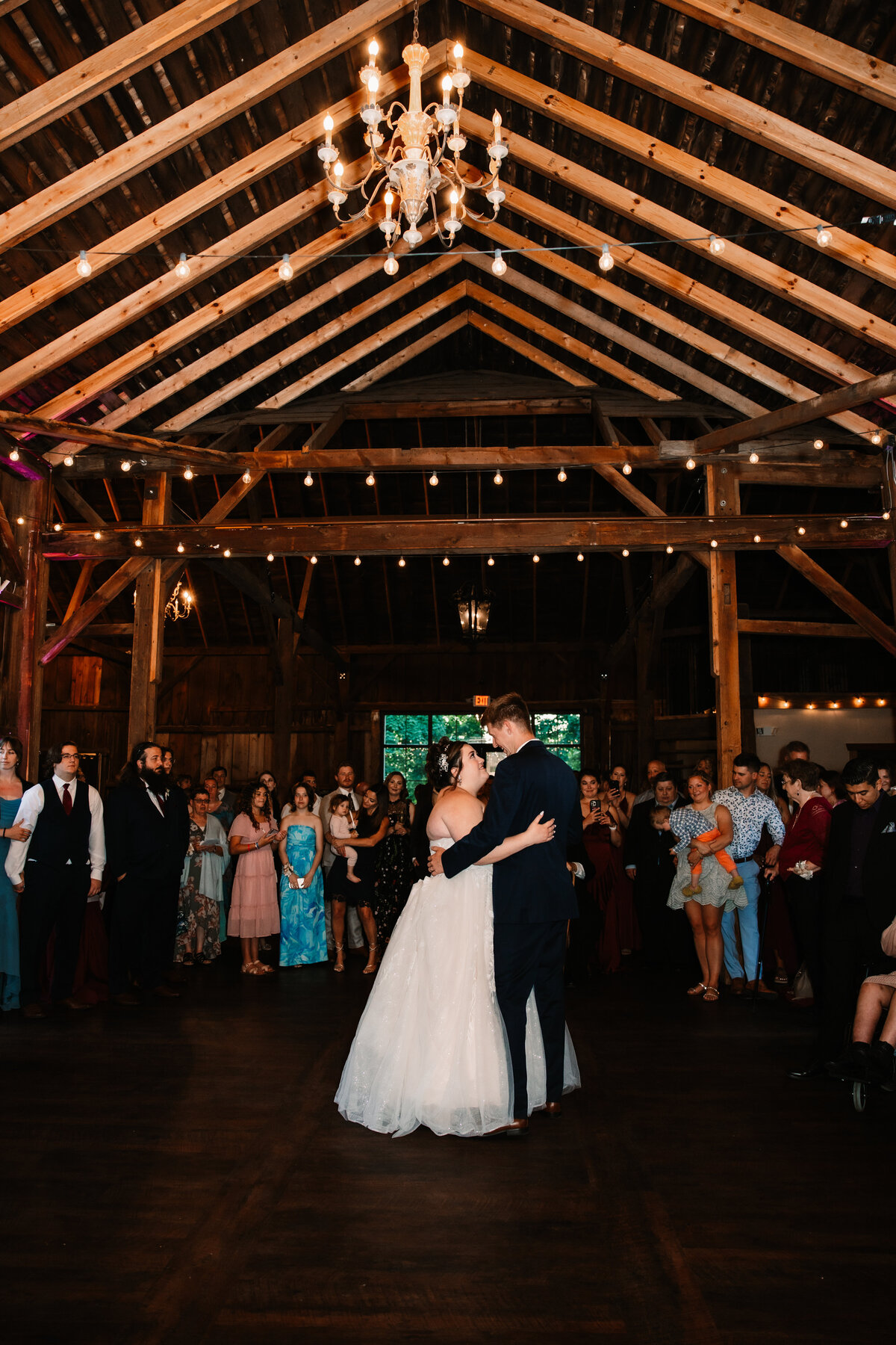 Newlyweds share their first dance alone on dance floor under chandelier