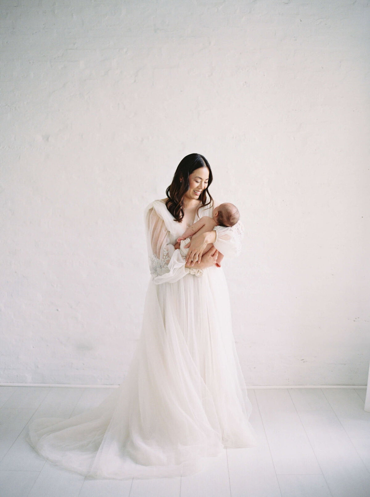 Mother cradling newborn during intimate Bay Area newborn photography session.