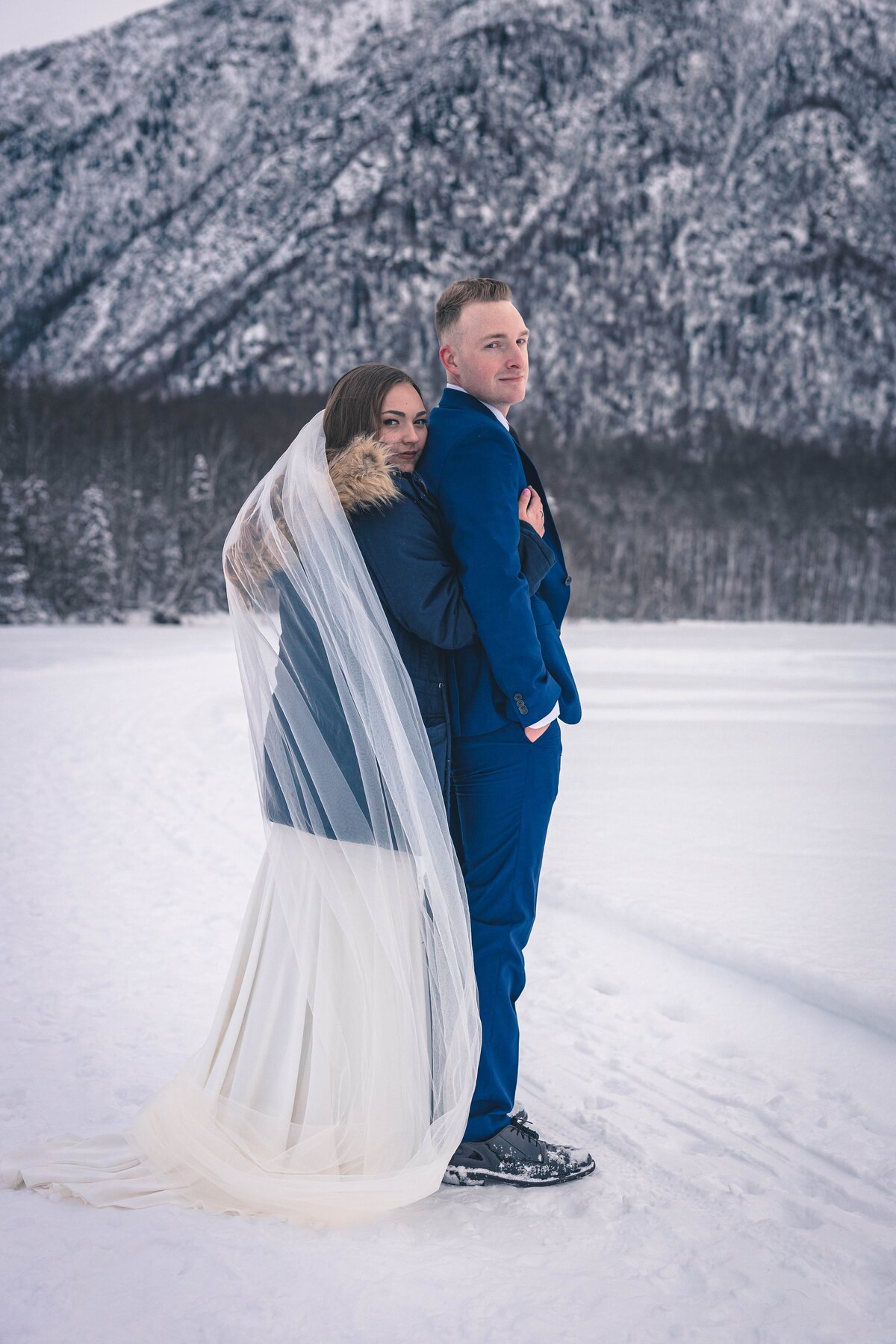 A brides gown wraps itself around a newlywed couple on Mirror Lake, Alaska
