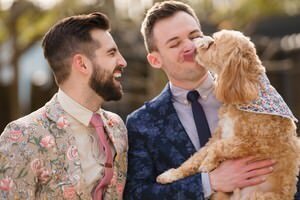 Two grooms in floral and blue suits with golden doodle dog at St Augustine wedding photoshoot by professional wedding photographers