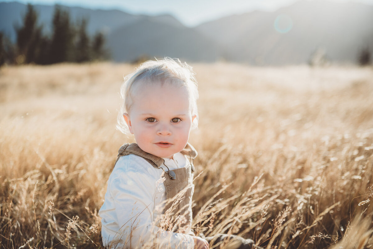 a boy sitting in the grass for a family photoshoot in wanaka