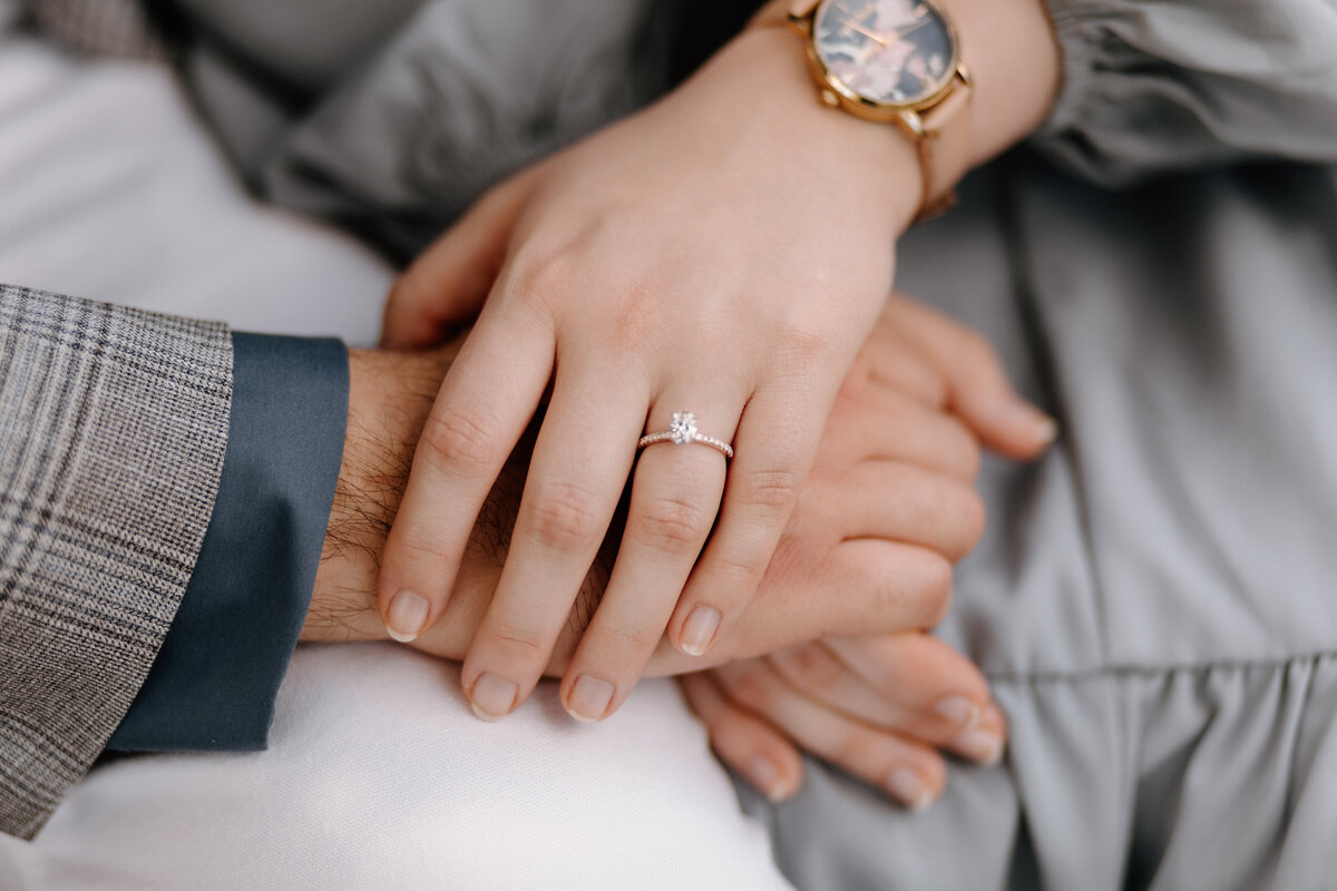 man and woman holding hands showing off engagement ring