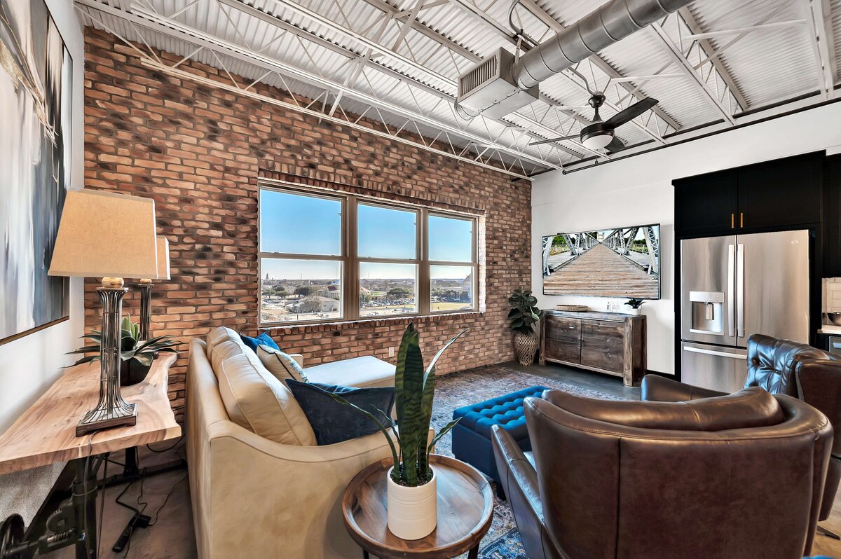 Living area with exposed brick and view of downtown in this one-bedroom, one-bathroom rental condo in the historic Behrens building just blocks from the Magnolia Silos and Baylor University in downtown Waco, TX.