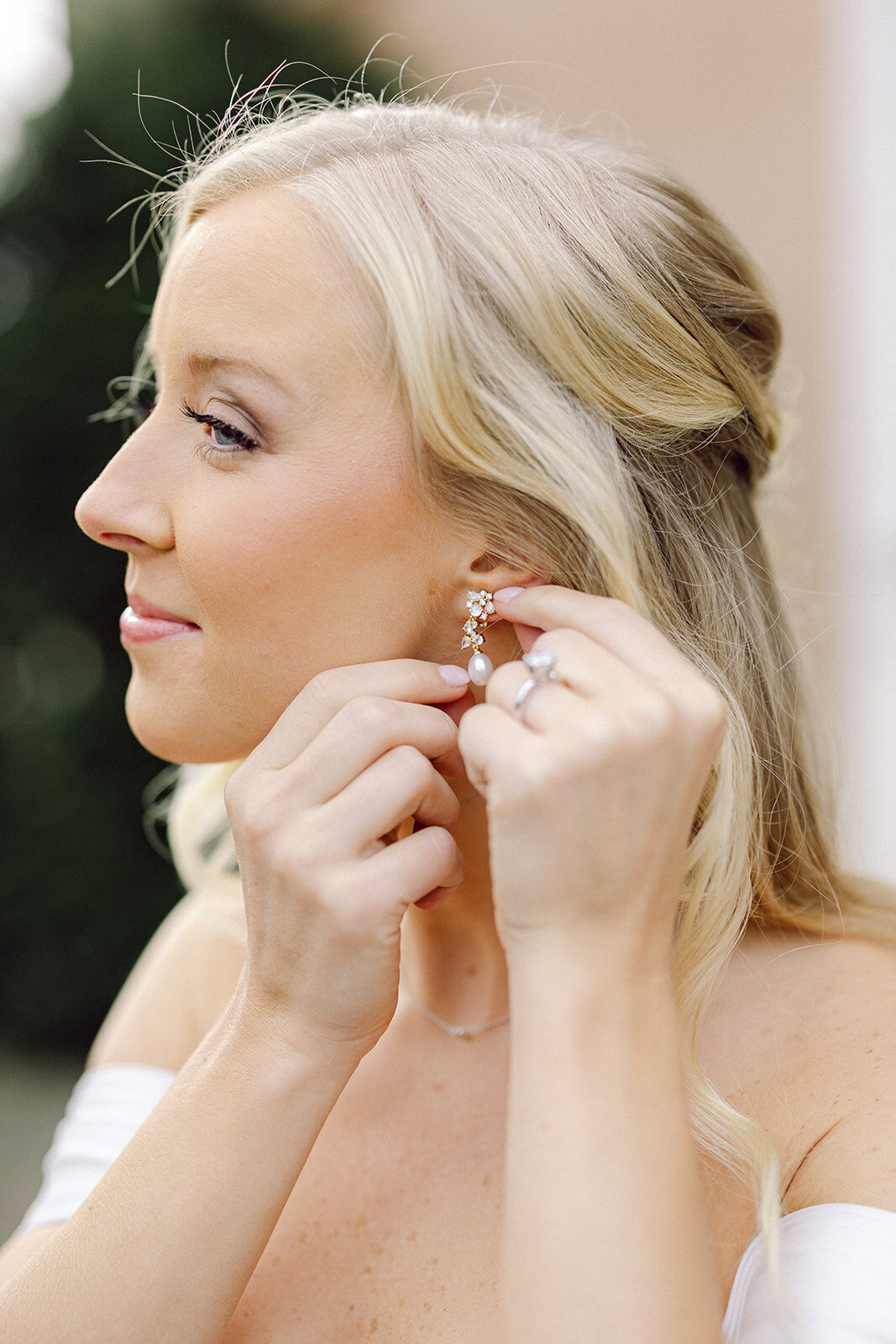 woman putting earrings in on her wedding day