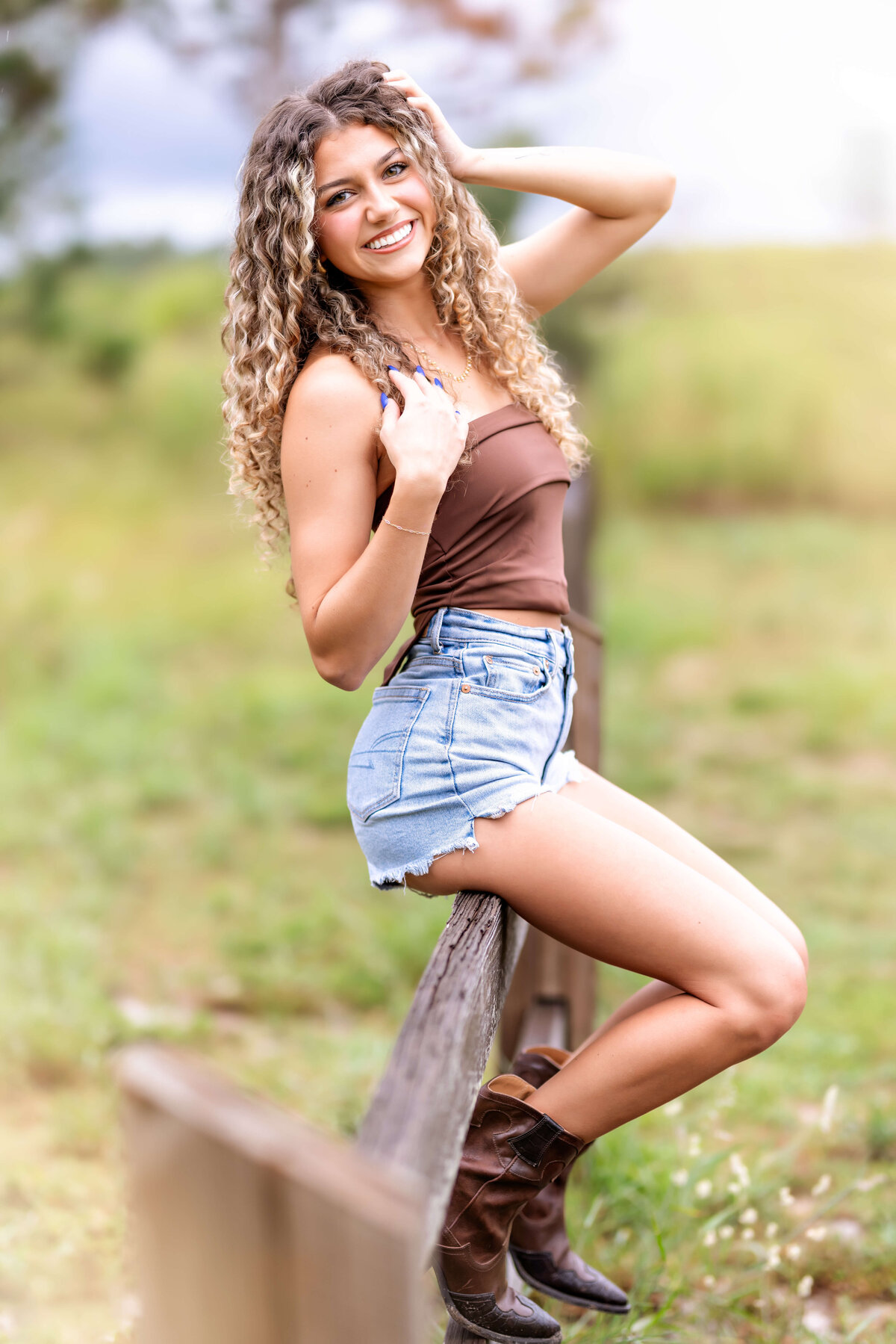 High school senior sitting casually on a fence during her Winter Garden photo session.