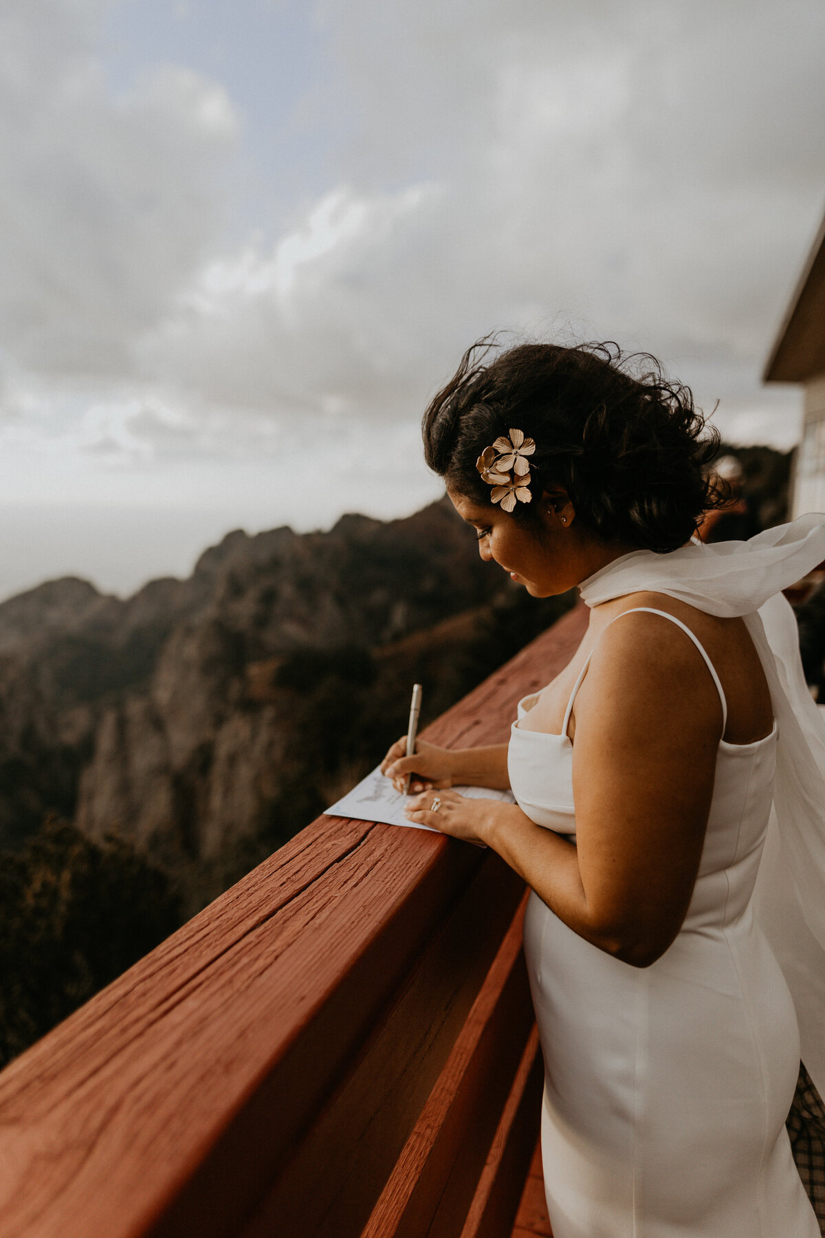 bride and groom signing paperwork on Sandia Peak Tramway boardwalk overlooking Albuquerque