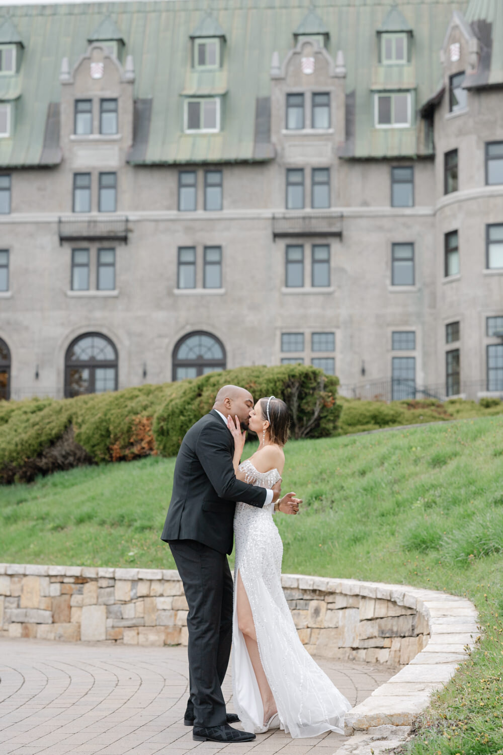 Epic photo of the bride and groom kissing in front of a stunning manor in Greater Montreal — a powerful and majestic moment captured against a grand architectural backdrop