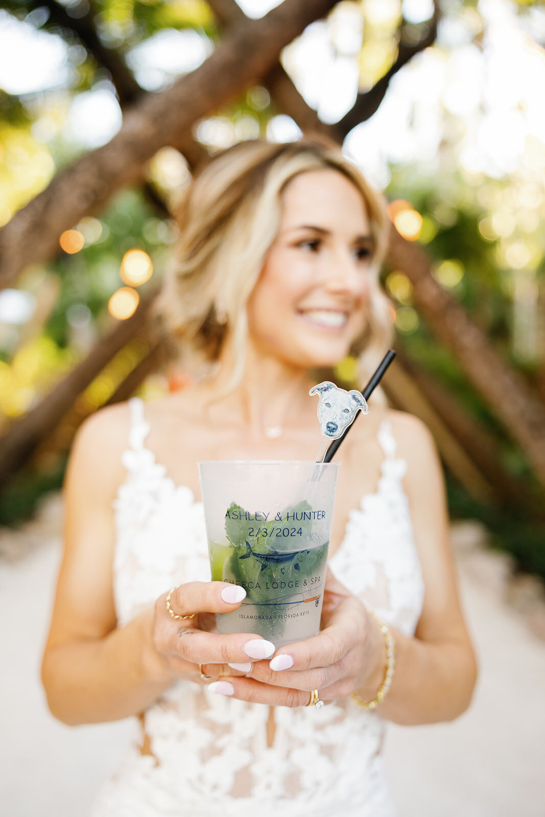Ashley holds a refreshing cocktail garnished with a tropical fruit slice, smiling during cocktail hour.