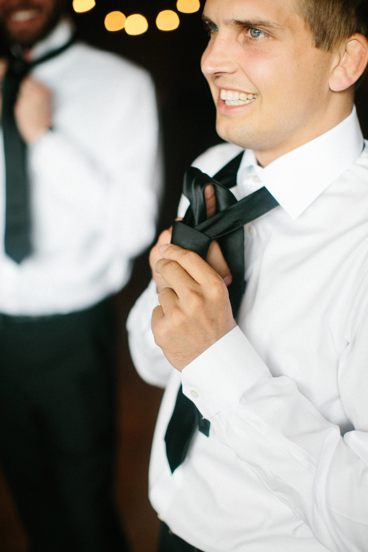 groom tying tie on wedding day in philadelphia