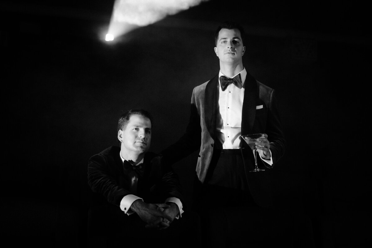 Black and white image of two grooms looking at the camera for their photo session pre-wedding ceremony.