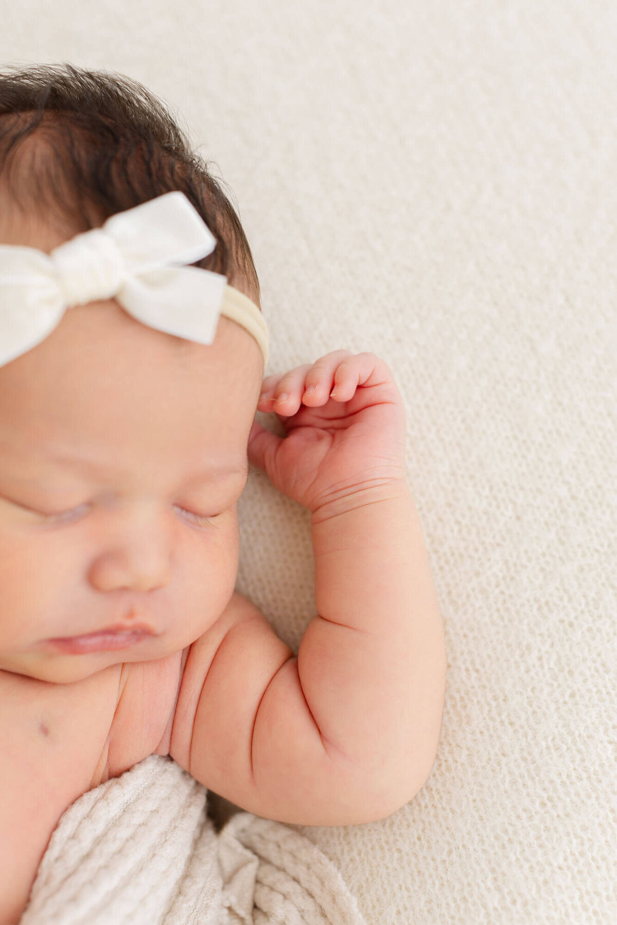 close up photo of baby's arm raised up by head, with face blurred out in the foreground