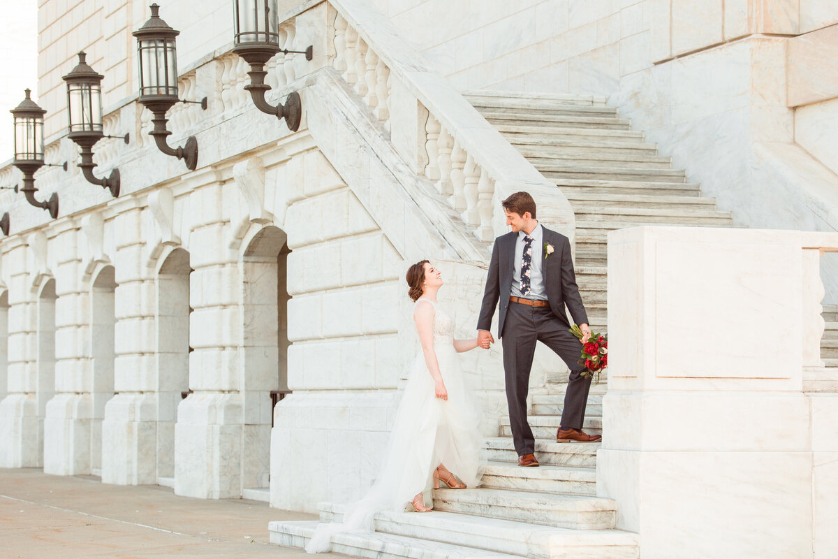 Groom looks back at bride as he leads her up the steps at the Detroit Institute of Art.