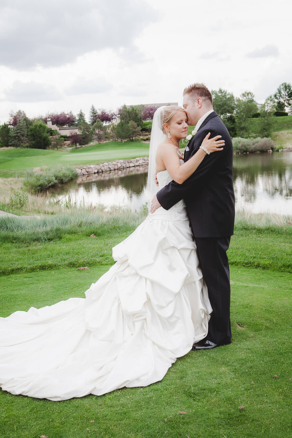 A bride and groom embrace after their wedding on a golf course.