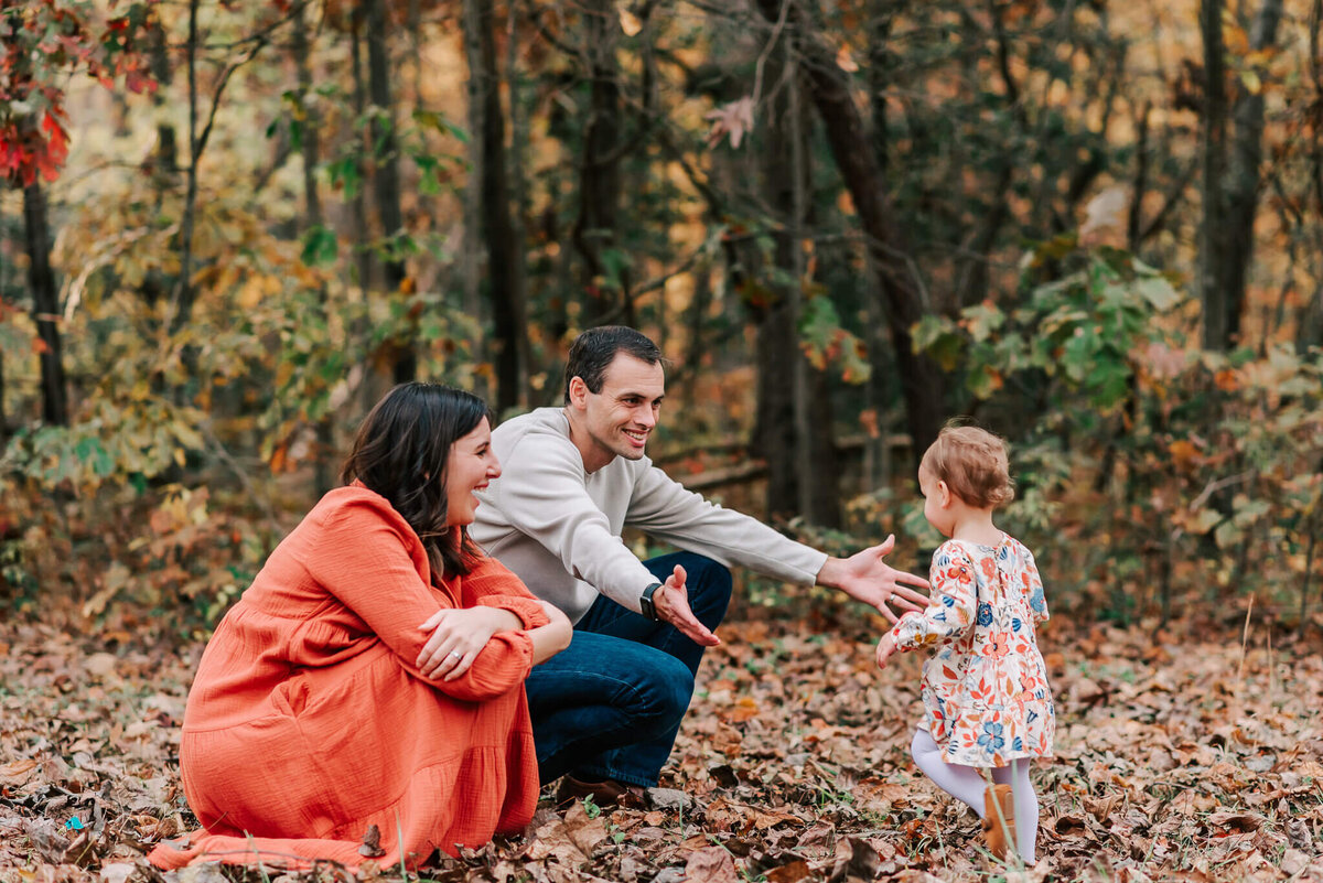 A child joyfully running into her father's arms while the mother watches