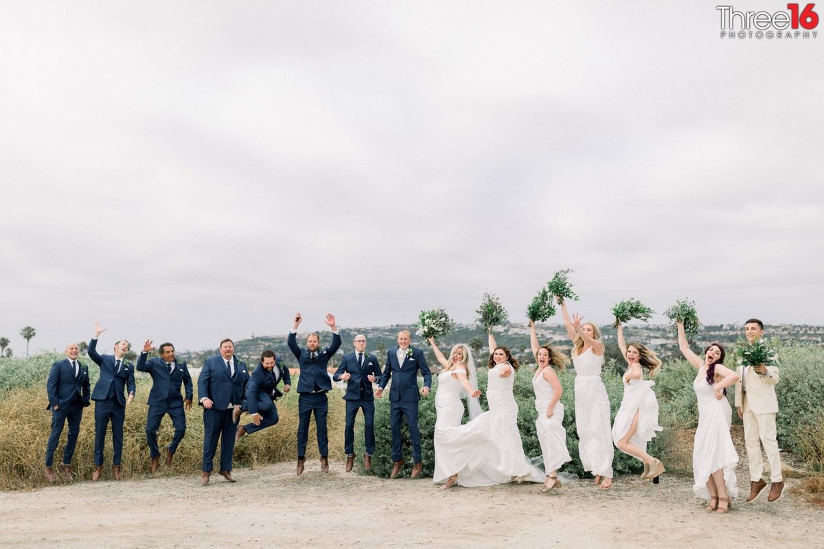 Bridal Party jumps for joy with ocean in background