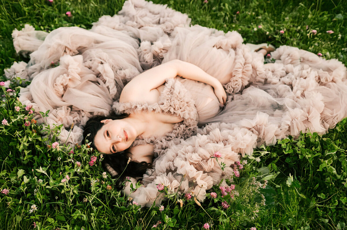 Springfield Mo maternity photography of pregnant mom laying in a field of flowers holding her baby bump