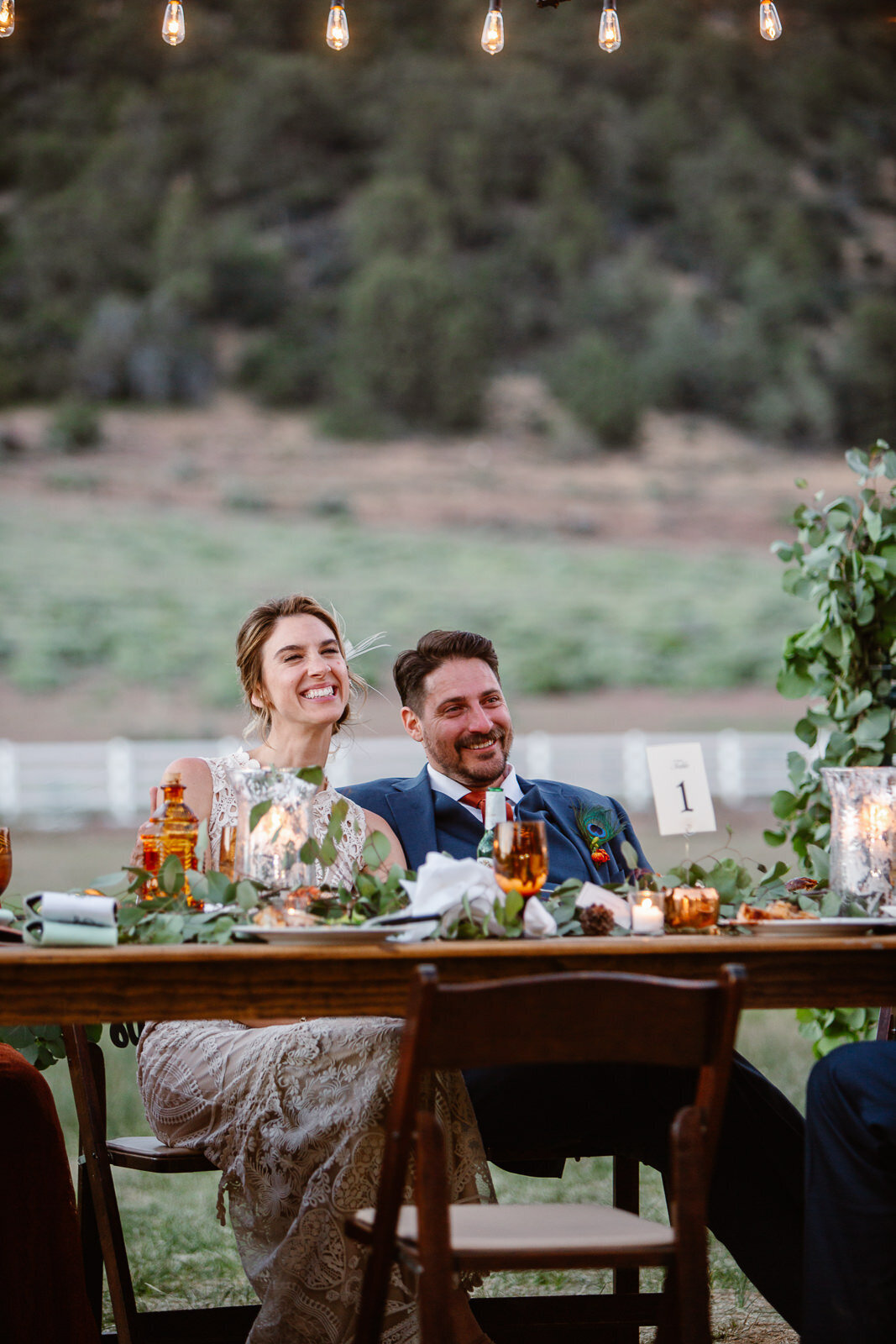 Ali and Brian sit at their table, smiling joyfully.