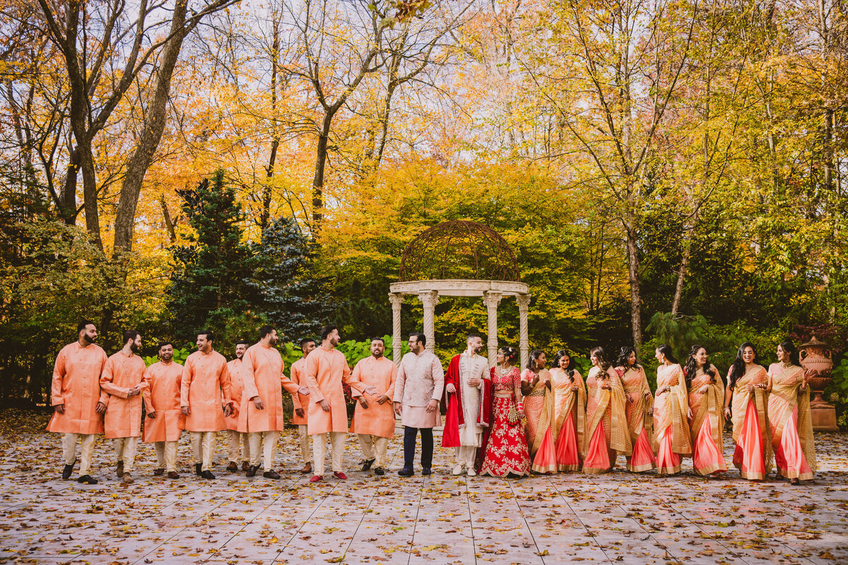 Indian wedding bride and groom walking with the bridal party in the fall at crystal plaza