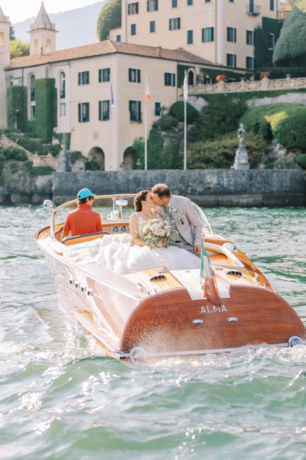 Bröllopspar pussas i en båt utanför Villa Balbianello