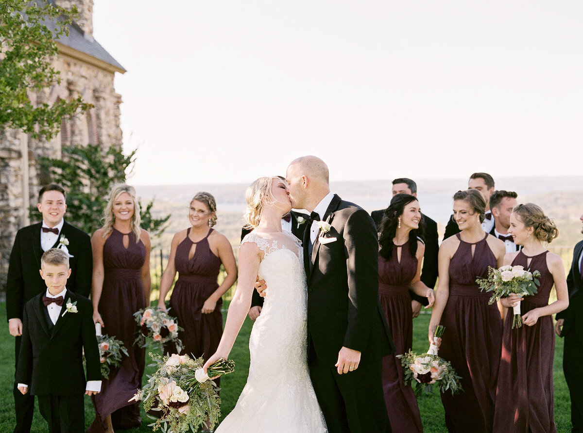 bride and groom kissing while bridesmaids and groomsmen celebrate