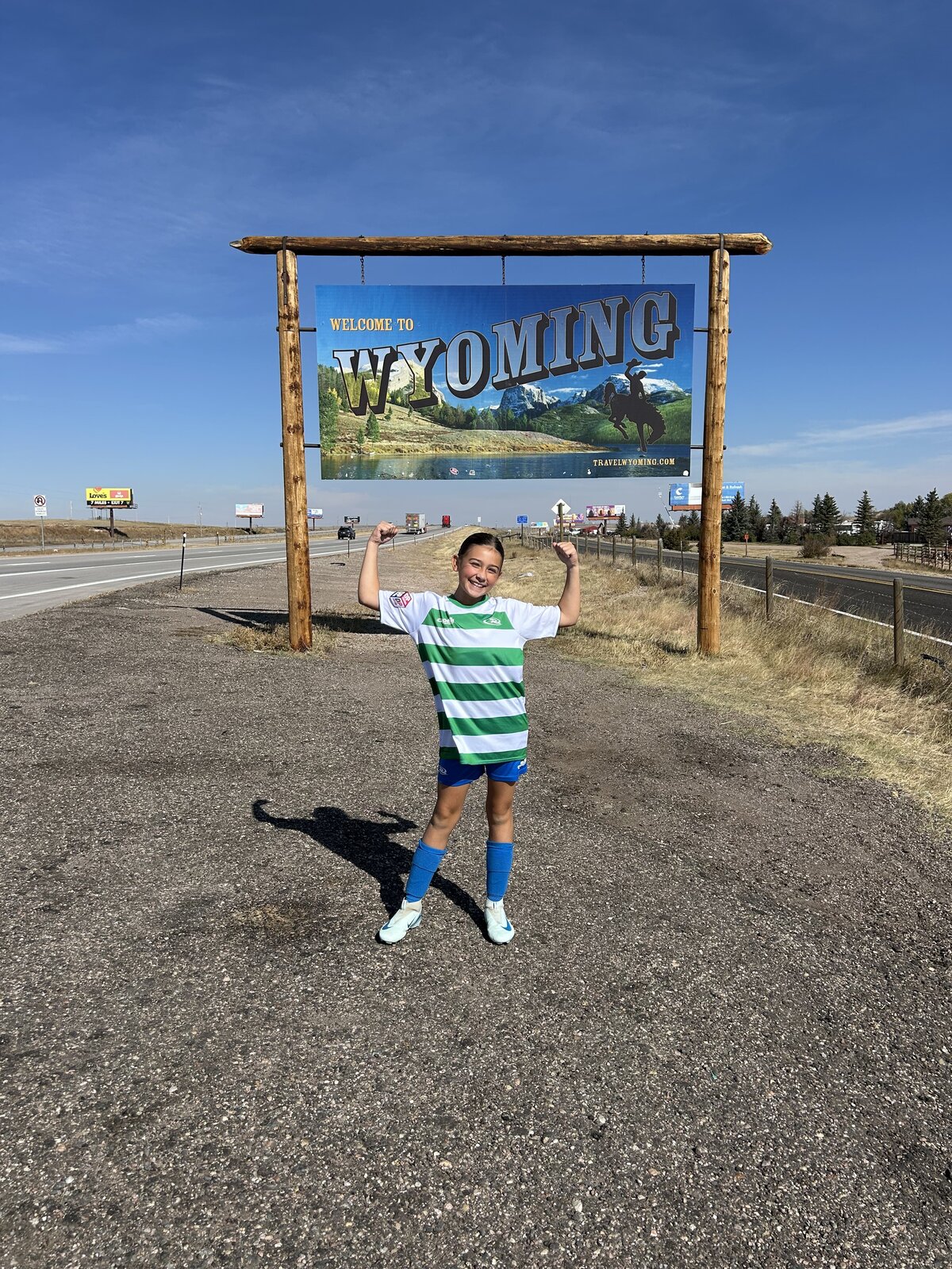 Young soccer player poses for photo in front of Wyoming sign