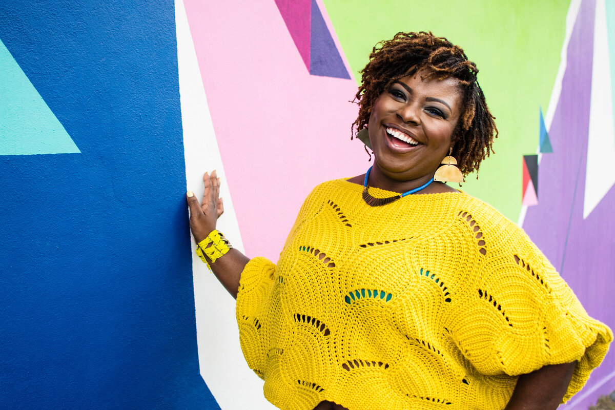 Laughing woman poses against a multicolored mural wall