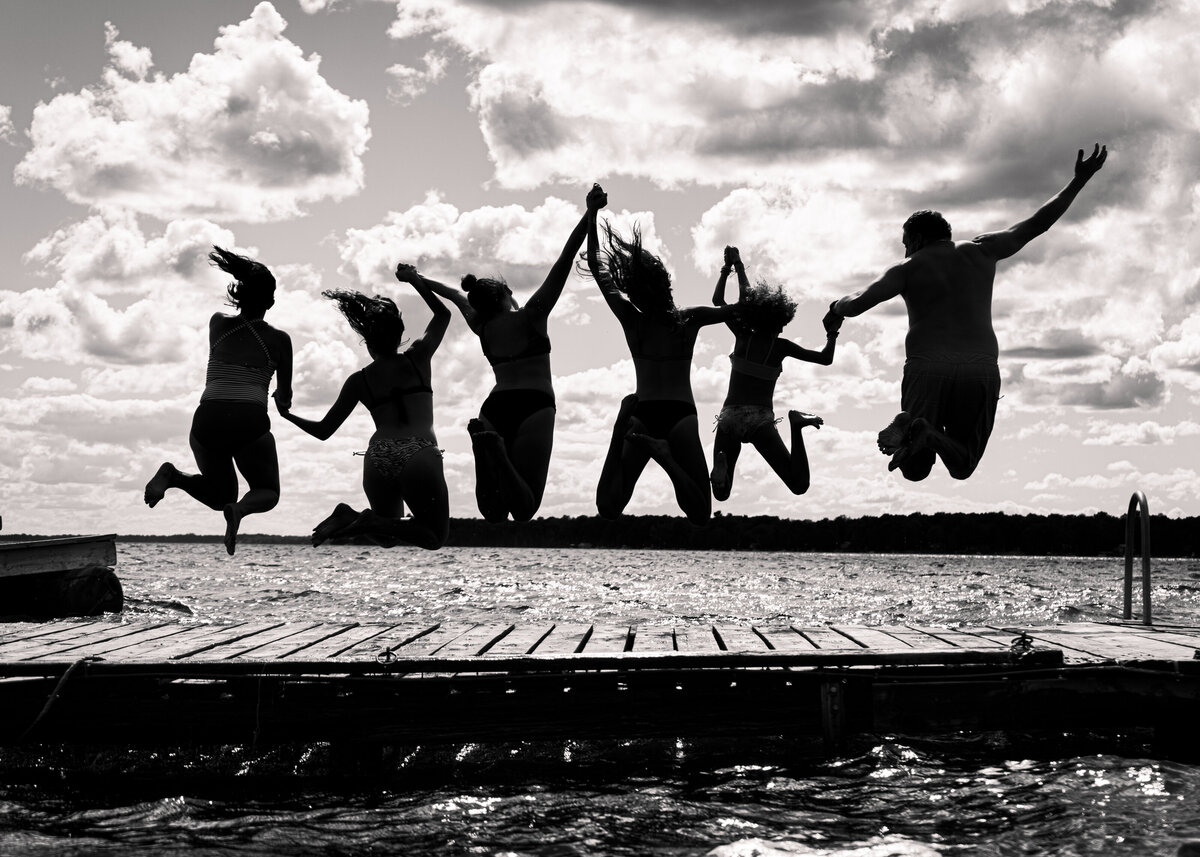 Black and white portrait of a family jumping into water