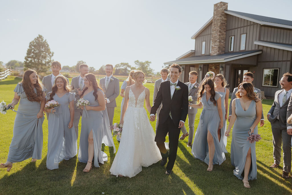 Wedding party walking across the lawn in front of the barn