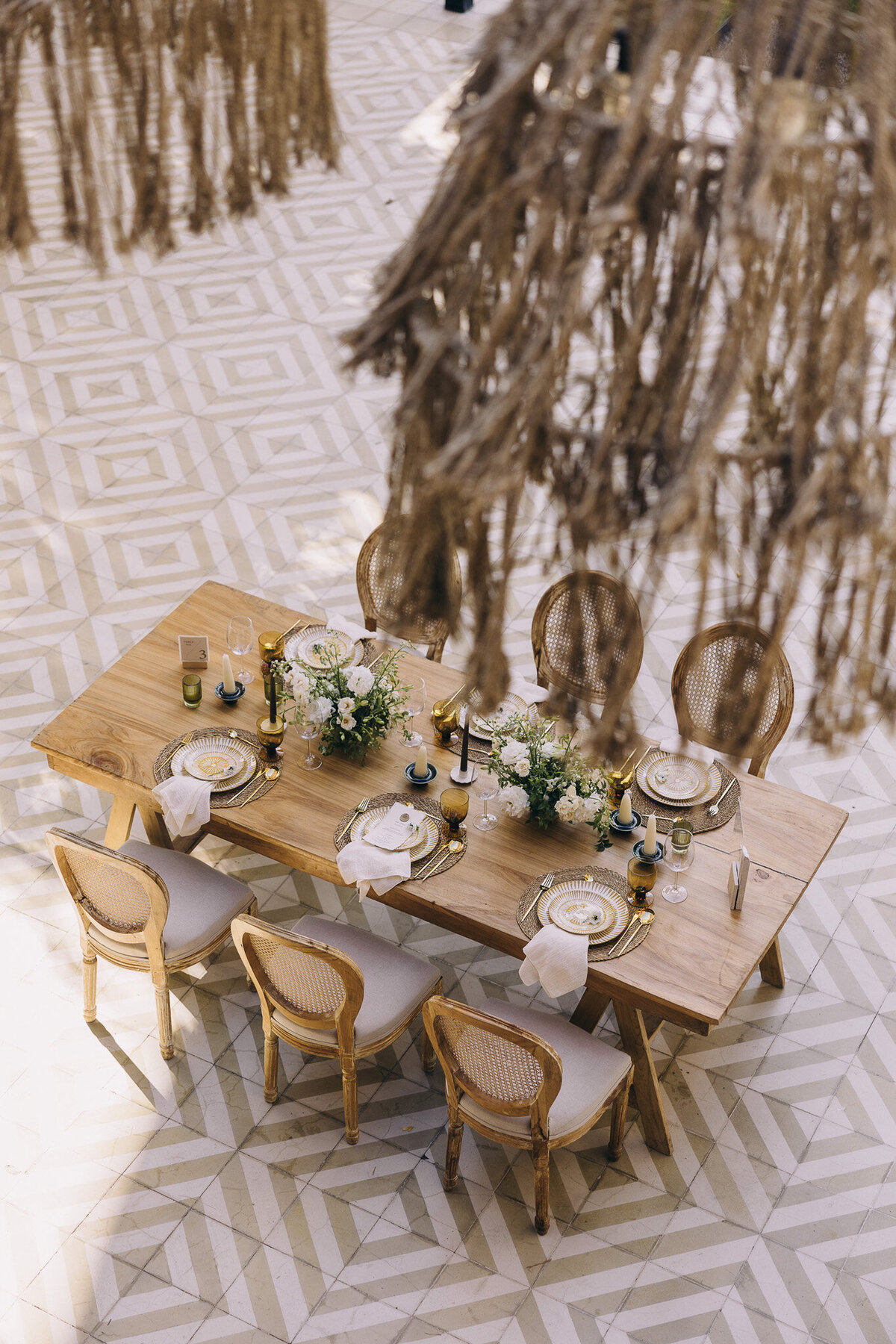 Luxury destination wedding reception featuring brown wood tables, ivory flowers, and sage décor
