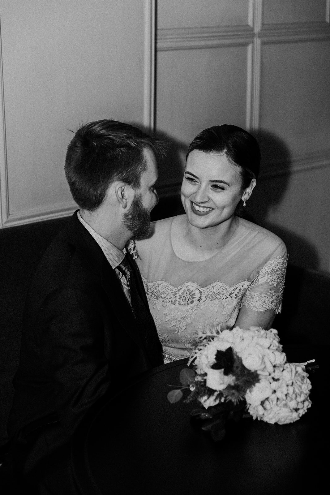 Just Married photo session couple sits in the Talbott Hotel bar and laughs together